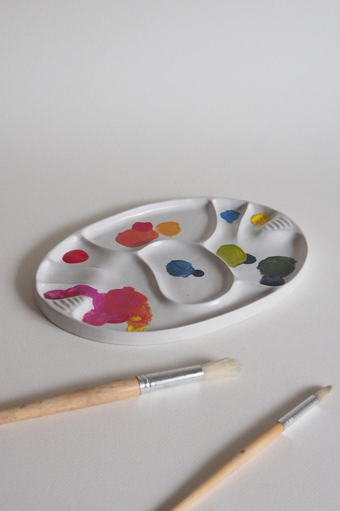 Koala palette covered in paint with paint brushes on the side